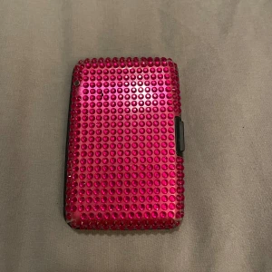 Rosa glittrig plånbok - Säljer en superfin rosa plånbok täckt med glittriga paljetter. Den har en hård utsida och flera fack inuti för kort och kontanter. Köparen står för frakten💞