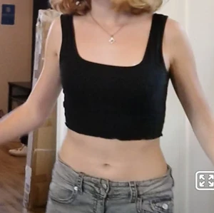 Svart croppad linnetopp - Säljer en svart croppad linnetopp i ett mjukt och stretchigt material. Perfekt för sommardagar eller som ett lager under en hoodie. Toppen har en enkel och stilren design med breda axelband.