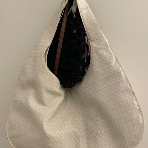 Beige axelväska med flätat mönster - Säljer en superfin beige axelväska med ett elegant flätat mönster. Perfekt för både vardag och fest! Väskan har en stilren design och är rymlig nog för alla dina essentials. Ett måste för den stilmedvetna! 👜✨