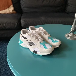 Reebok sneakers i vitt och turkos - Säljer ett par snygga Reebok sneakers i vitt med turkosa och svarta detaljer i storlek 40,5. Knappt använda! 