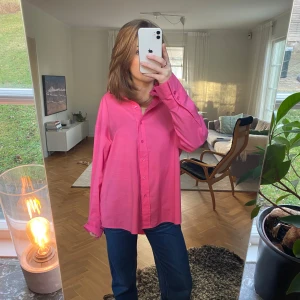 Rosa långärmad skjorta - Säljer en snygg rosa långärmad skjorta i normal passform. Perfekt för både vardag och fest! Skjortan har knappar framtill och är i ett mjukt material som känns skönt mot huden. Passar bra till jeans eller kjol för en stilren look💓