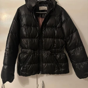Svart pufferjacka från Esprit - Säljer en snygg svart pufferjacka från Esprit i storlek 34. Jackan har en dragkedja framtill och praktiska fickor med dragkedjor. Perfekt för kalla dagar med sin vadderade design. Passar både till vardags och lite finare tillfällen. Jackan är aldrig använd. 