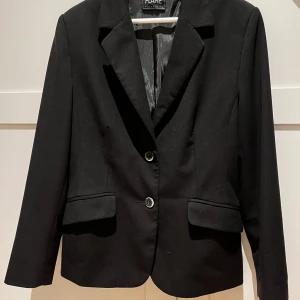 Kavaj  - En snygg kavaj i normal längd med knappar fram och två fickor med lock .