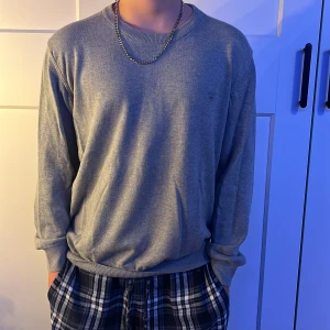 Grå tröja från GANT - Säljer en stilren grå tröja från GANT i mycket bra skick. Den är långärmad och perfekt för både vardag och lite finare tillfällen. Materialet känns mjukt och bekvämt, och den har en liten broderad logga på bröstet. Passar perfekt till höst- och vårgarderoben!