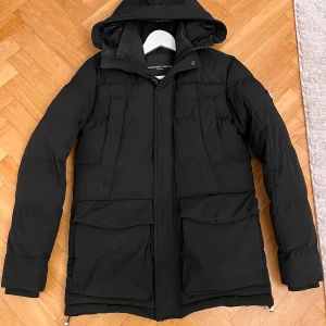 Svart pufferjacka från Alessandro Zavetti - Säljer en svart pufferjacka från Alessandro Zavetti i storlek XS. Jackan har fickor framtill. Perfekt för kalla vinterdagar med sin varma och quiltade design. Den är i mycket bra skick och redo för nya äventyr! Om du vill ha en jacka som ingan annan har då är den här den rätta