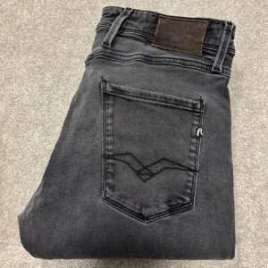 Grå jeans från Replay - Säljer ett par snygga grå jeans från Replay i mycket bra skick. De har en klassisk femficksdesign med snygga detaljer på bakfickorna. Perfekta för både vardag och fest!