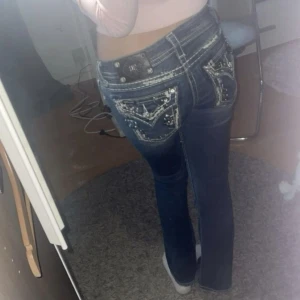 Mörkblå jeans med broderade fickor - Snygga mörkblå miss me jeans med broderade detaljer på bakfickorna och glitter.  De har en normal passform och är perfekta för både vardag och fest. Jeansen har en klassisk femficksdesign och är gjorda i ett slitstarkt denimtyg.❤️ 