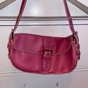 Rosa axelväska med spänne - Säljer en superfin rosa axelväska! Väskan har ett gulligt spänne framtill och justerbar axelrem. 🌺