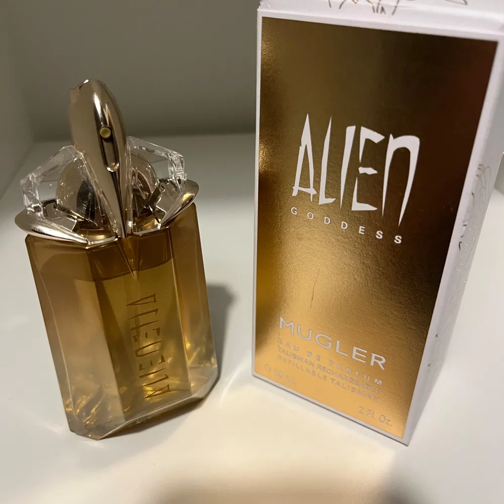 Säljer en lyxig Alien Goddess Eau de Parfum från Mugler. Flaskan är i en elegant guldton med en unik, futuristisk design. Den är påfyllningsbar och rymmer 60 mL. Perfekt för den som vill ha en doft som sticker ut och känns exklusiv. Passar både till vardags och fest!. Parfym.