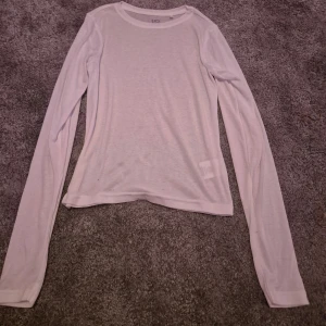 Vit långärmad tröja från 157 - Säljer en enkel och stilren vit långärmad tröja från 157. Den är lite genomskinlig.Perfekt för lager-på-lager under kyligare dagar. Tröjan är i ett mjukt och bekvämt material av 65% polyester och 35% viskos. Passar till både vardag och avslappnade tillfällen.