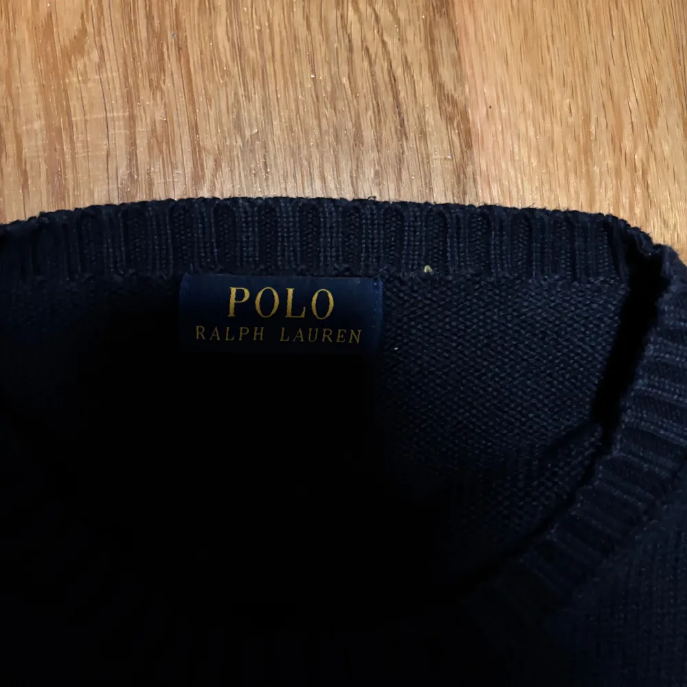 Säljer en snygg mörkblå tröja från Ralph Lauren med det klassiska röda logotypbroderiet på bröstet. Tröjan är i bra skick och har ribbade muddar vid ärmslut och nederkant. Perfekt för både höst och vinter!. Tröjor & Koftor.