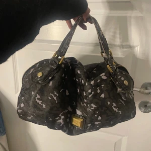 Svart och vit mönstrad handväska - Säljer en snygg svart handväska med vitt mönster och gulddetaljer. dragkedja är tyvärr trasig , handtaget lite slit och lite smutsig inuti, därv pris!! Haft den i några år nu men har ej kvitto kvar 