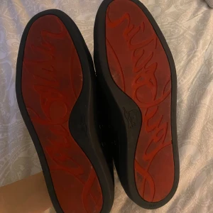 Svarta Louboutin skor med röd sula - Säljer ett par stilrena svarta Christian Louboutin skor i skinn med en cool röd sula. De har klassisk snörning och är perfekta för både vardag och fest. Skorna är i mycket bra skick och passar till de flesta outfits. Perfekt för dig som vill ha en touch av lyx i din skogarderob! (Pris går att diskutera)