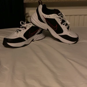 Nike Air monarch i svart och vitt - Säljer ett par Nike Air monarch i svart och vitt med röda detaljer. Skorna har en klassisk design med snörning och en bekväm sula. Perfekta för både vardag och träning. De är i mycket bra skick och redo för nya äventyr! Aldrig använt dem här testat dem inne men inte gått ut med dem. Skit bra skor om du ska jogga eller gå ut och gå eller köra nån sport t.ex. innebandy. Nypris 900. Pris kan diskuteras 