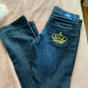 Mörkblå jeans från Victoria Beckham - Säljer ett par snygga mörkblå jeans från Victoria Beckham. De har en cool guldbroderad krona på bakfickan och är i mycket bra skick. Perfekta för både vardag och fest! 