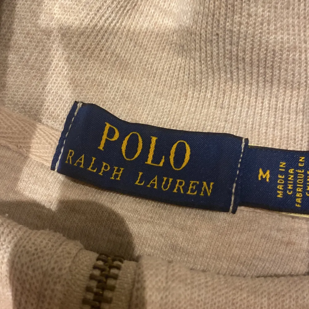 Säljer en snygg beige tröja från Polo Ralph Lauren i storlek M. Tröjan har en dragkedja framtill och det klassiska logotypbroderiet på bröstet. Perfekt för både vardag och lite finare tillfällen. Superbekväm och stilren!. Tröjor & Koftor.