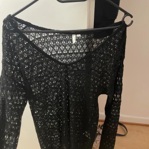 Svart spetsmönstrad tröja från H&M - Säljer en elegant svart spetsmönstrad tröja från H&M i storlek XS. Perfekt för en kväll ute eller en festlig tillställning. Tröjan har en v-ringad design och långa ärmar. Superfin att matcha med ett par jeans eller en kjol! 🖤