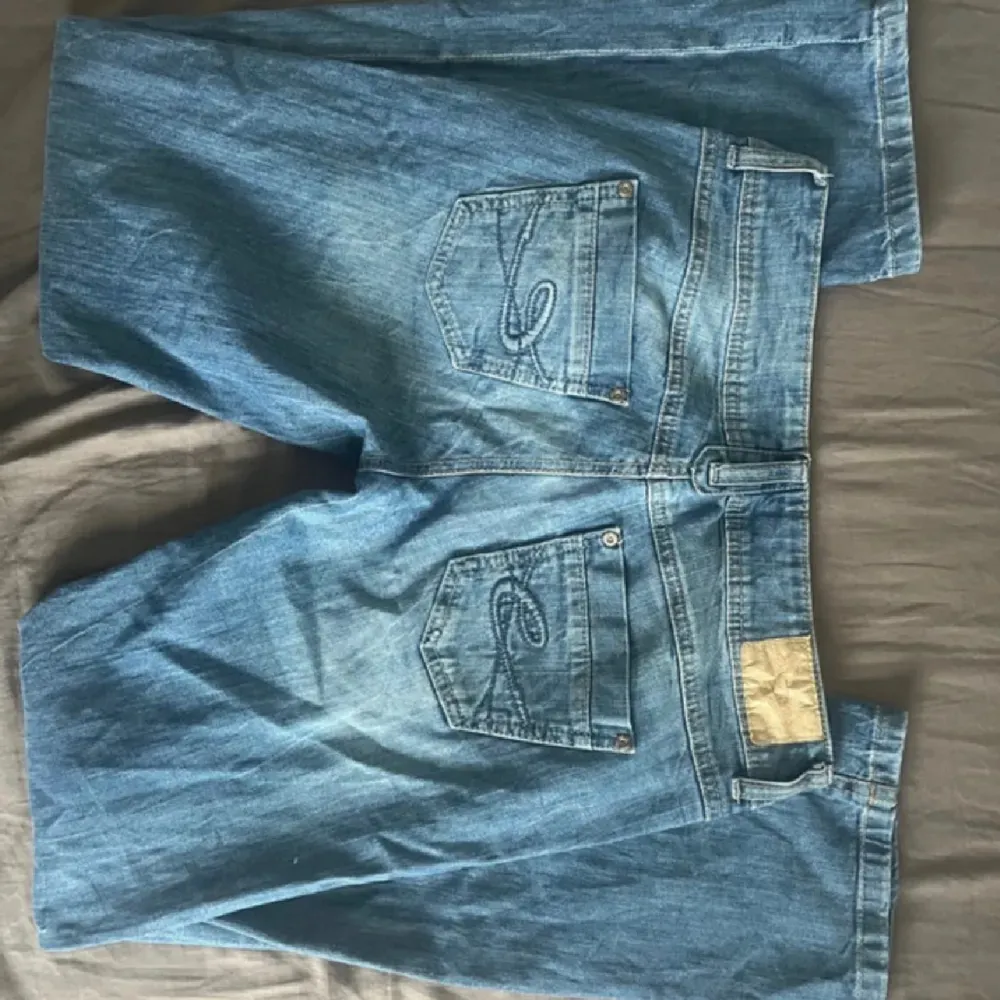 Säljer ett par klassiska blå jeansshorts från C&A. De har en normal passform med två knappar som får ens kropp att se bra ut och dragkedja fram. Shortsen har fem fickor och är perfekta för sommaren. De är i bra skick och redo för nya äventyr!. Jeans & Byxor.