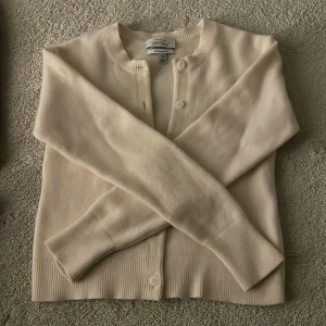 Vit kofta  - Säljer en superfin vit kofta från other storys i mycket bra skick. Den är gjord av mjukt material och har knappar framtill. Perfekt för höst och vår, och den är långärmad med ribbat material längst ner. Ser ut som ny. Inga täcken på nopprig och är så mjuk därav inte använda så mycket