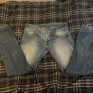  dondup jeans  - Säljer ett par snygga blå jeans från dondup med coola slitningar och en klassisk femficksdesign. De har en normal passform och är perfekta för en avslappnad stil. 