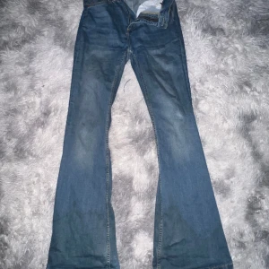 Blå flare jeans - Säljer ett par snygga blå flare jeans i storlek L. De har en klassisk design med dragkedja och knapp framtill. Perfekta för en avslappnad stil och passar till alla tillfällen. De är i bra skick och redo för en ny ägare!