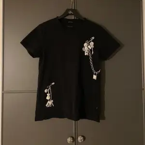 Svart Marc Jacobs T-shirt med snygga detaljer. Fått några mini hål som visas på bilderna, tre jättesmå nära kragen och en lite längre ned.