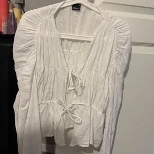 Vit blus från Gina Tricot - Säljer en söt vit blus från Gina Tricot i storlek S. Blusen har en v-ringad design med knytband framtill och långa ärmar. Perfekt för vår och sommar, och kan enkelt kläs upp eller ner beroende på tillfälle. Den är endast använd 1 gång och det är inga defekter, den är alltså helt som ny. 