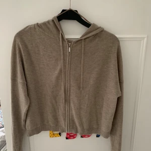 Beige hoodie med dragkedja från intimissemi  - Säljer en supermysig beige hoodie  i bra skick. Den har dragkedja framtill och en skön huva med knytband. Perfekt för höst och vår när man vill ha något bekvämt och stilrent. Passar till både jeans och leggings!