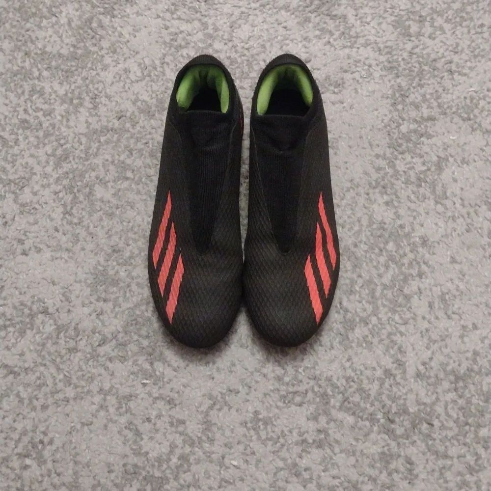 Säljer ett par svarta Adidas crazyfast fotbollsskor i mycket bra skick. De har en snygg design med röda gröna detaljer. Perfekta för fotbollsträning eller match. Skorna är utan snörning.. Skor.