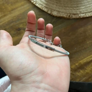 Elegant silverarmband - Säljer ett stilrent och elegant armband i silver. Det har en enkel design med en tunn kedja och en slät platta i mitten. 