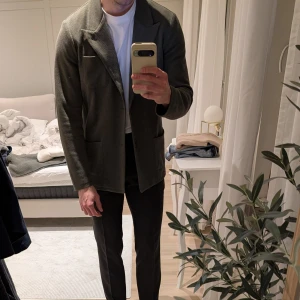 Grön kavaj från John Henric i M - Säljer en stickad Grön kavaj från John Henric i M i mycket bra skick. Perfekt för både vardag och festliga tillfällen. Passar bra till höst och vår. Storleken är M. Modellen är 183cm och 77kg.