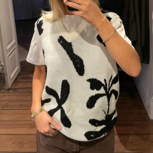 Vit och svart stickad väst från Obey - Säljer en vit stickad väst från Obey med svart abstrakt mönster. Perfekt för lager-på-lager. Den har en v-ringad hals och är i mycket bra skick. Passar perfekt till både vardag och fest. Orginalpris 999:-