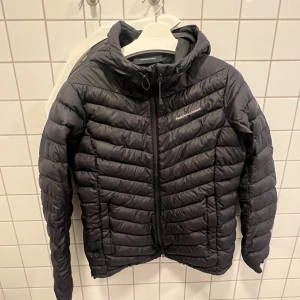 Svart dunjacka från Peak Performance - Säljer en snygg svart dunjacka från Peak Performance i storlek L. Den är perfekt för kalla dagar med sin quiltade design och huva. Jackan har dragkedja framtill och är i mycket bra skick. Perfekt för både höst och vinter!  Om någon är intresserad så säljer jag den för 1600 kr då den kostar 3199 i butik. Pris kan diskuteras!!
