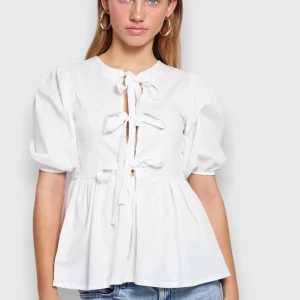 Vit blus med knytning - Säljer en superfin vit blus med knytning framtill. Den har puffiga kortärmar och en luftig passform som ger en romantisk känsla. Perfekt för både vardag och fest! Nyskick och perfekt för både sommar och vinter. Bara att skriva om du har någon fråga eller vill ha egna bilder!!💕