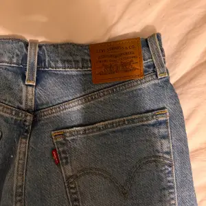 Säljer ett par Levi's Ribcage Straight jeans i ljusblå denim. De har en hög midja och en straight passform & slitage på ena knäet. Sparsamt använda! 