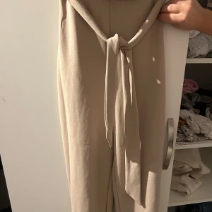 Beige byxor från Boohoo - Säljer ett par snygga beige byxor från Boohoo. De är högmidjade med ett knytband i midjan för extra stil. Perfekta för både vardag och fest! 🥳