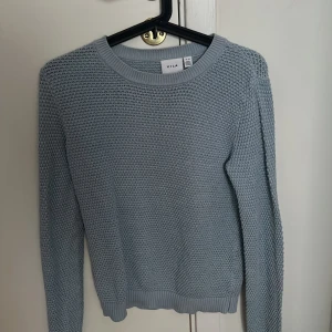 Ljusblå stickad tröja från Vila - Säljer en superfin ljusblå stickad tröja från Vila i storlek XS. Perfekt för kyliga dagar med sin mysiga och mjuka känsla. Tröjan har en rund halsringning och långa ärmar, vilket gör den idealisk för både höst och vinter. Passar perfekt till jeans eller kjol för en avslappnad look.