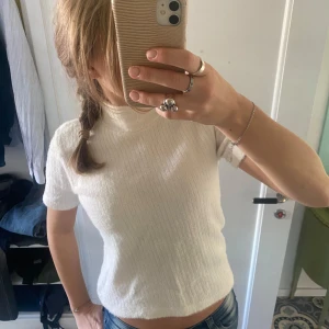 Vit ribbad topp från Zara - Säljer en superfin vit ribbad topp från Zara. Den har en hög krage och korta ärmar. Är i storleken L men skulle säga att den passar XS-S. Den är i superbra skick och är fin till allt🤍🤍