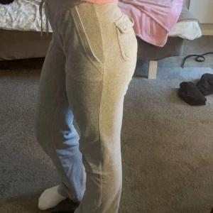 Grå mjukisbyxor från Juicy Couture - Superbekväma grå mjukisbyxor från Juicy Couture i storlek XXS. De har en loose passform med snörning i midjan och praktiska fickor både fram och bak. Perfekta för en chill dag hemma eller en avslappnad promenad. 🩶Tryck inte på köp nu utan kontakta mig vid intresse istället 🩶super bra pris! Bra skick.🩶