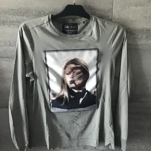 Olivgrön långärmad tröja med tryck - Säljer en olivgrön långärmad tröja från Limitato med ett coolt tryck av en person på framsidan. Tröjan har ett synligt. Skriv om ni är intresserade