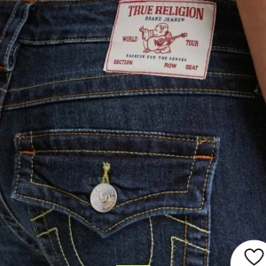 Mörkblå jeans från True Religion - Säljer ett par snygga mörkblå jeans från True Religion. De har en bootcut-stil och är lågmidjade med coola detaljer som kontrastsömmar och knappar på bakfickorna. Perfekta för en avslappnad men stilren look!         Köpte dem av en tjej här på plick och fick hem igår men dem var förstora så säljer därför vidare dem
