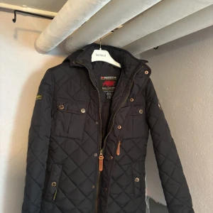 Svart quiltad jacka från Geographical Norway - Säljer en snygg svart quiltad jacka från Geographical Norway. Den har dragkedja och knappar framtill, samt praktiska fickor med knappar. Perfekt för höst och vår! Jackan är i mycket bra skick och har en normal passform.