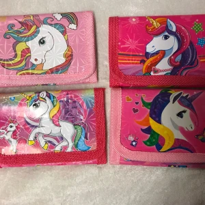 Barn Plånbok  - Säljer fyra supergulliga plånböcker med olika enhörningsmotiv. De är i härliga färger som rosa, lila och regnbågsfärger. Perfekta för att hålla dina pengar och kort säkra med stil! 🦄.  55kr/st ✨