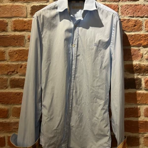 Ljusblå skjorta från Burberry! - Säljer en stilren ljusblå skjorta från Burberry  i herrstorlek XS. Skjortan har långa ärmar och klassisk krage, perfekt för både vardag och fest. Den är i bra skick och har diskreta knappar framtill. Passar utmärkt till både jeans och kostymbyxor. Mvh Måns!