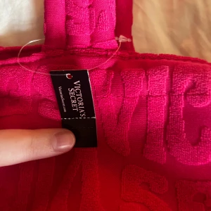 Rosa shoppingväska från Victoria's Secret - Säljer en superfin limited edition rosa shoppingväska från Victoria's Secret som jag fick i New York. Väskan har ett mönster med upphöjda bokstäver och är perfekt för en dag på stan eller stranden. Den är rymlig och har bekväma handtag. Perfekt för dig som vill ha något både snyggt och praktiskt! 💖