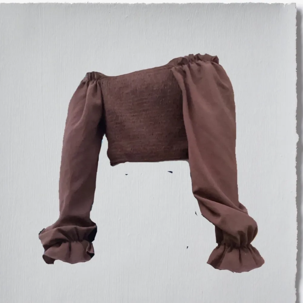 Säljer en superfin brun offshoulder topp med långa ärmar och volangdetaljer vid ärmsluten. Toppen har en söt knytning framtill. Yläosat.