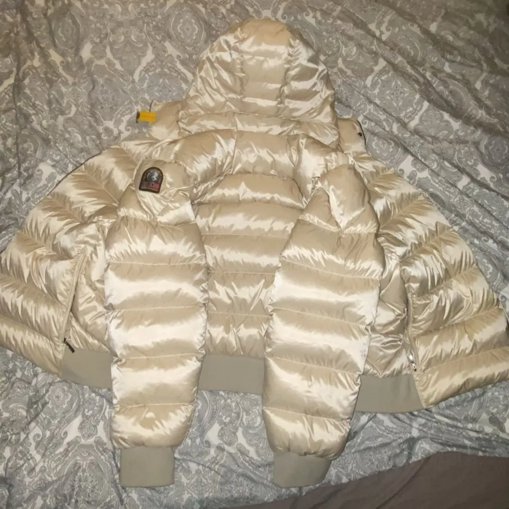 Säljer en snygg beige pufferjacka från Parajumpers i mycket bra skick. Jackan har en glansig finish och är perfekt för kalla dagar. Den har en huva och dragkedja framtill, samt ribbstickade muddar vid ärmsluten. Märkeslogga på ärmen ger en extra touch och är perfekt för dom kalla dagarna under vintern!! Skriv och ställ gärna frågor. Pris kan diskuteras . Jackor.