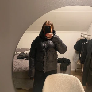 Svart pufferjacka - Säljer en svart pufferjacka i mycket bra skick. Den är perfekt för kalla vinterdagar med sin tjocka vaddering och långa ärmar. Jackan har en dragkedja framtill och en hög krage för extra värme. Den är både snygg och praktisk, idealisk för vinterns alla äventyr!