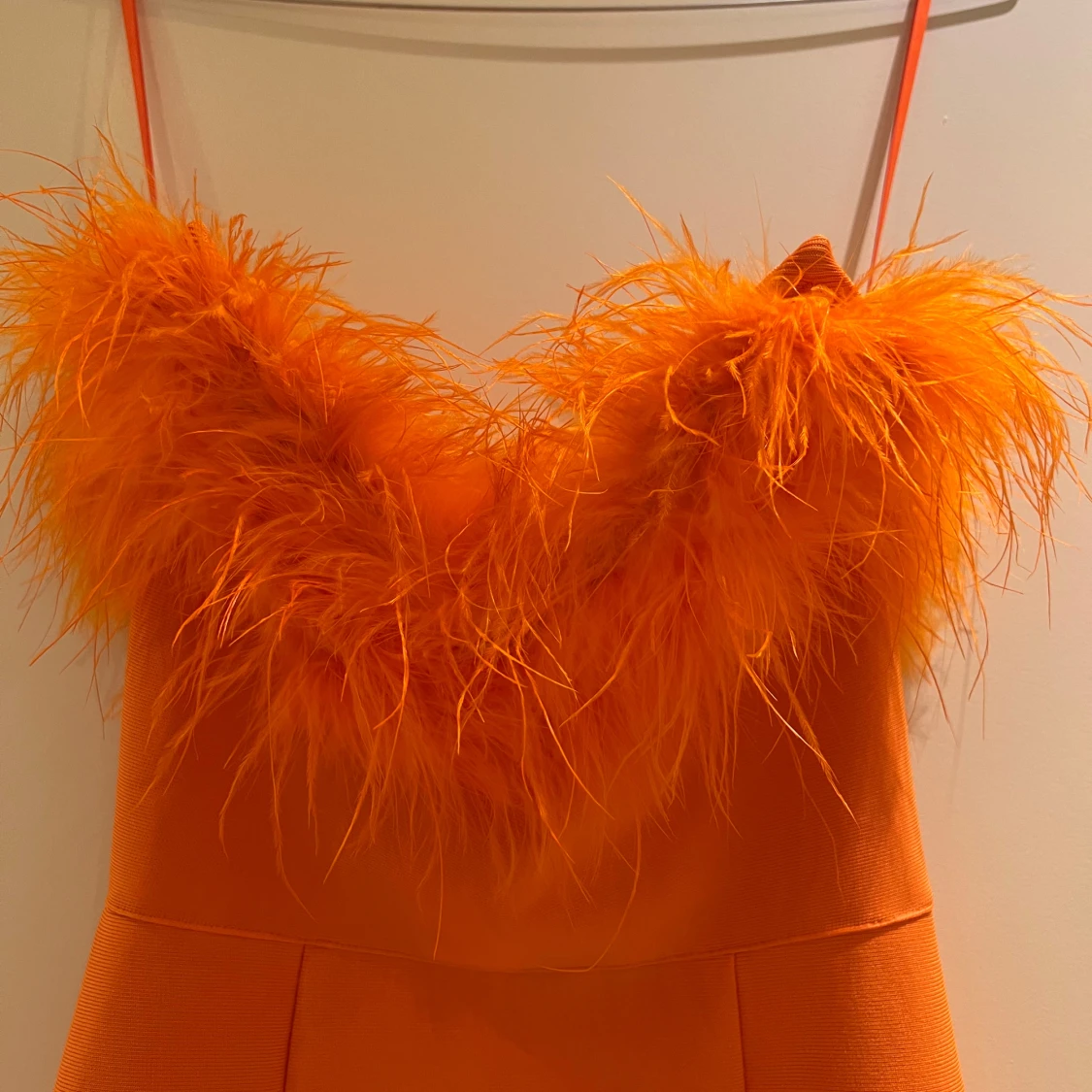 Orange klänning med fjäderdetaljer