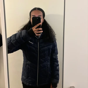 Mörkblå quiltad jacka med huva - Säljer en snygg mörkblå quiltad jacka från Everest. Den har en dragkedja framtill och en praktisk huva. Jackan är i bra skick. Storlek M men passsar även en person med storlek S/XS.